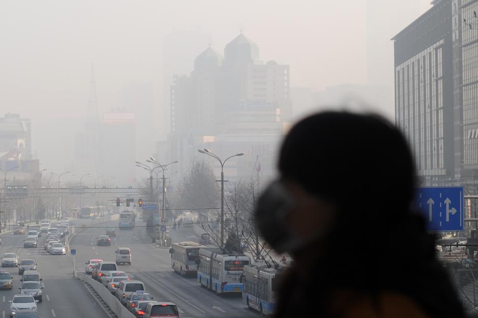 A woman wearing a face mask walks on an overpass in Beijing on January 16, 2014.  China's capital was shrouded in thick smog on January 16, cutting visibility down to a few hundred metres as a count of small particulate pollution reached more than 20 times recommended levels.        AFP PHOTO / WANG ZHAO