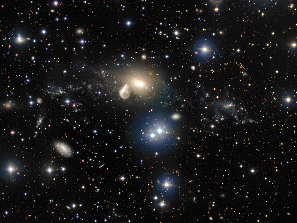 The spectacular aftermath of a 360 million year old cosmic collision is revealed in great detail in this image from ESO’s Very Large Telescope at the Paranal Observatory. Among the debris surrounding the elliptical galaxy NGC 5291 at the centre is a rare and mysterious young dwarf galaxy, which appears as a bright clump towards the right of the image. This object is providing astronomers with an excellent opportunity to learn more about similar galaxies that are expected to be common in the early Universe, but are normally too faint and distant to be observed by current telescopes.