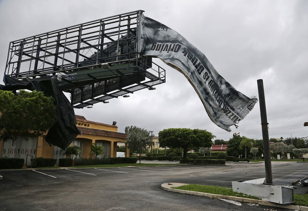 A billboard canvas flaps in the wind after Hurricane Matthew passed off shore, Friday, Oct. 7, 2016, in North Palm Beach, Fla.  Matthew was downgraded to a Category 3 hurricane overnight with the strongest winds of 120 mph just offshore as the storm pushed north, threatening hundreds of miles of coastline in Florida, Georgia and South Carolina.  (AP Photo/Wilfredo Lee)