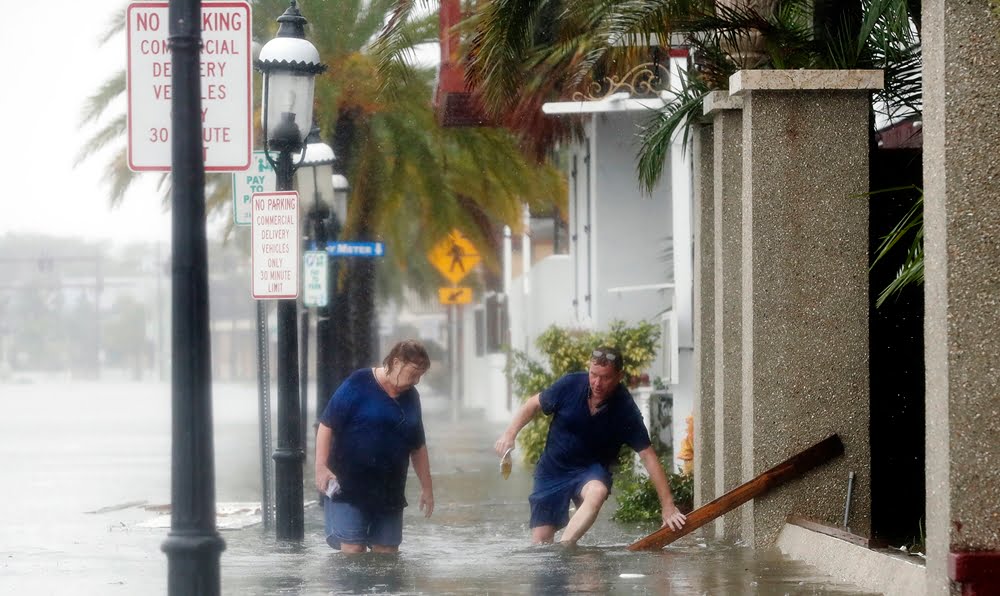 A man and a woman walk through flood waters from Hurricane Matthew, Friday, Oct. 7, 2016, in St. Augustine, Fla.  (AP Photo/John Bazemore)